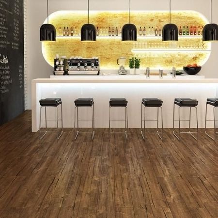 Moderner Barbereich mit schlichter weißer Theke, schwarzen Hockern, Pendelleuchten und einem beleuchteten Regal