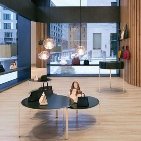 Eine moderne Boutique mit verschiedenen Handtaschen auf schwarzen Tischen, beleuchtet von stilvollen Hängelampen