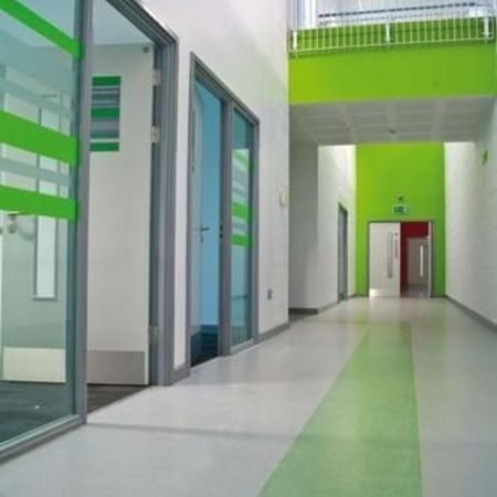 Ein moderner Korridor mit grünen Akzenten, mit gläsernen Büros und heller, einladender Beleuchtung