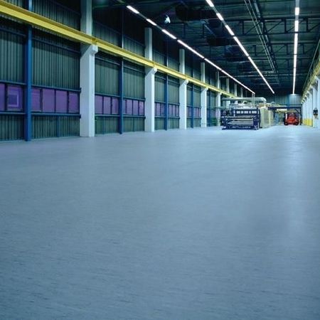 Geräumige Industriehalle mit glatten grauen Fußböden, hohen Decken und großen Toren