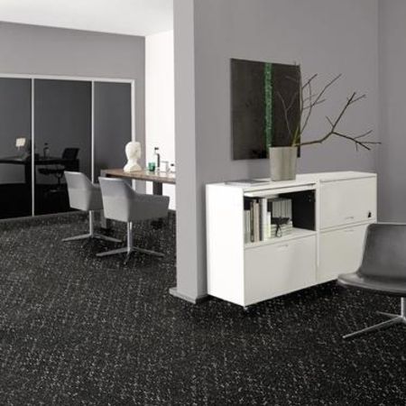 Büroeinrichtung mit einem schwarz gesprenkelten Teppich, minimalistischen weißen Möbeln und zeitgenössischem Dekor in gedeckten Farben