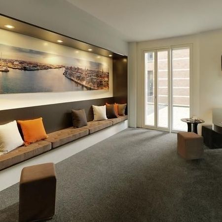 Lounge mit einer Wandmalerei, gepolsterten Sitzgelegenheiten, großen Fenstern und einer minimalistischen Einrichtung
